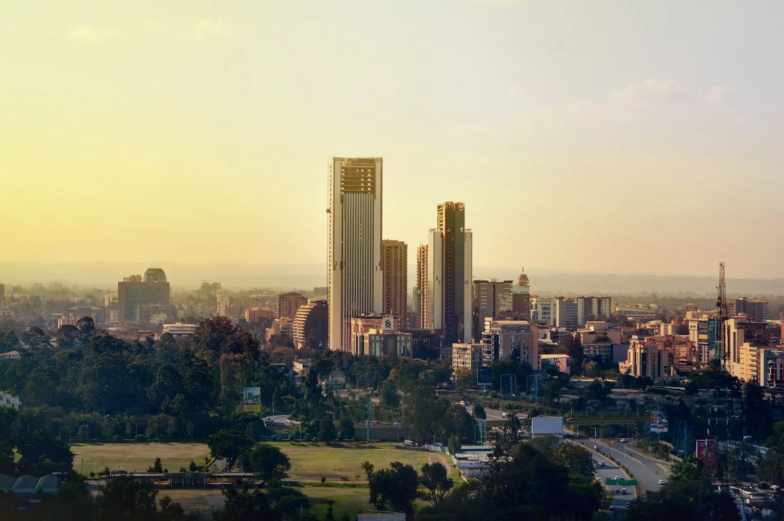 Nairobi skyline at golden hour, office towers rising over trees and a road